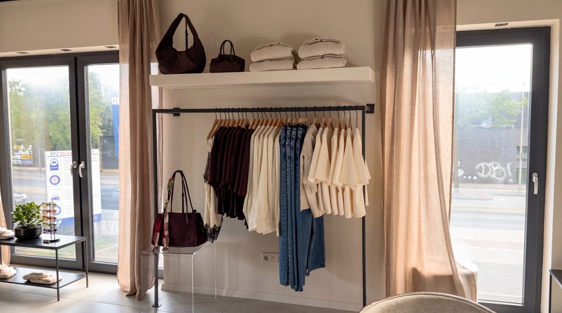 Wandregal mit Taschen in Bordeaux, darunter Strick und Jeans an der Stange